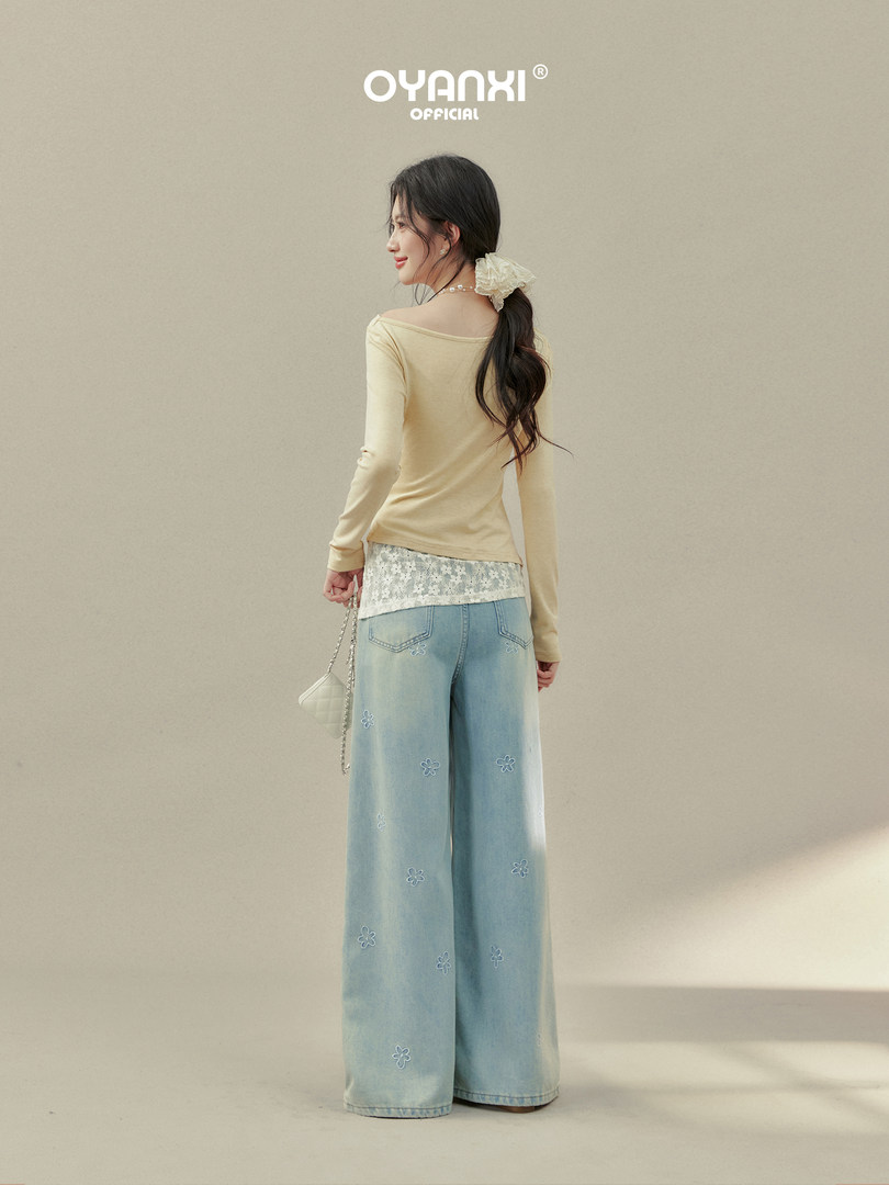Model wearing light blue wide-leg embroidered jeans with a cream top