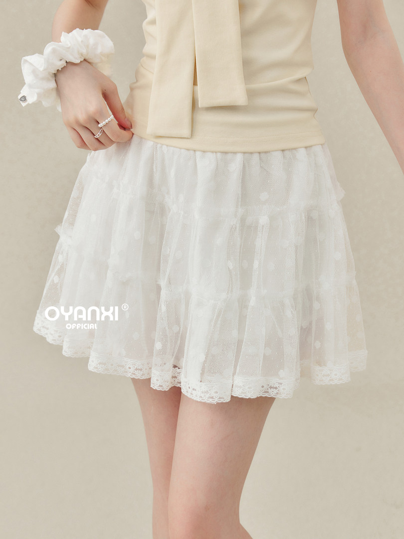 Model wearing a beige sleeveless top with a white lace tulle skirt