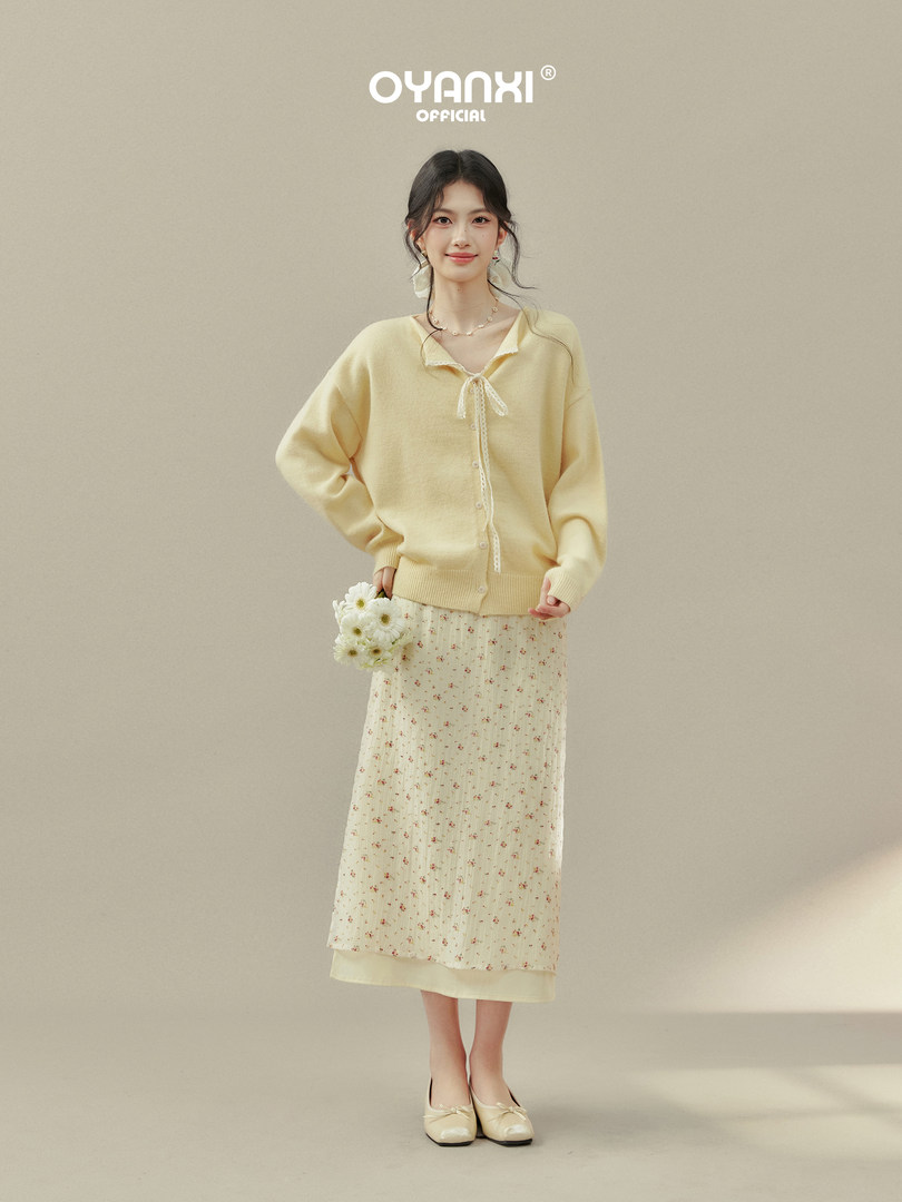 Model wearing a pale yellow cardigan and floral skirt outfit
