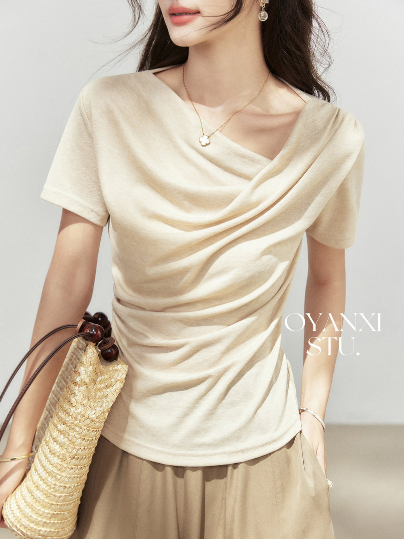 Woman wearing a cream draped short-sleeve top with a woven straw bag