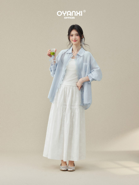 Model wearing a light blue sheer button-up shirt with a white layered skirt