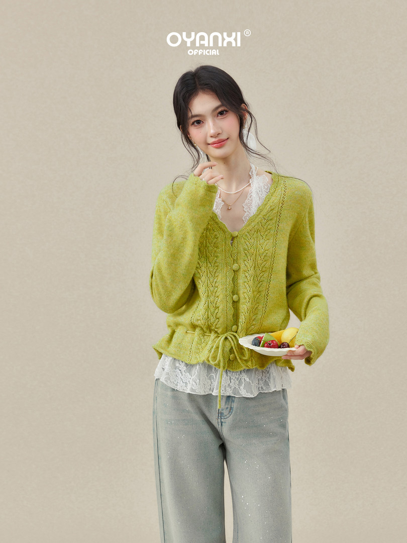 Model wearing a light green knit cardigan over a lace top with jeans