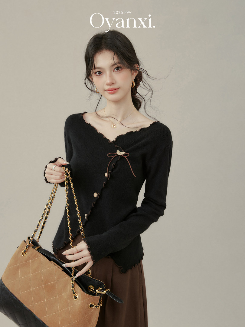 Model wearing a black long-sleeve top with a brown chain-strap handbag