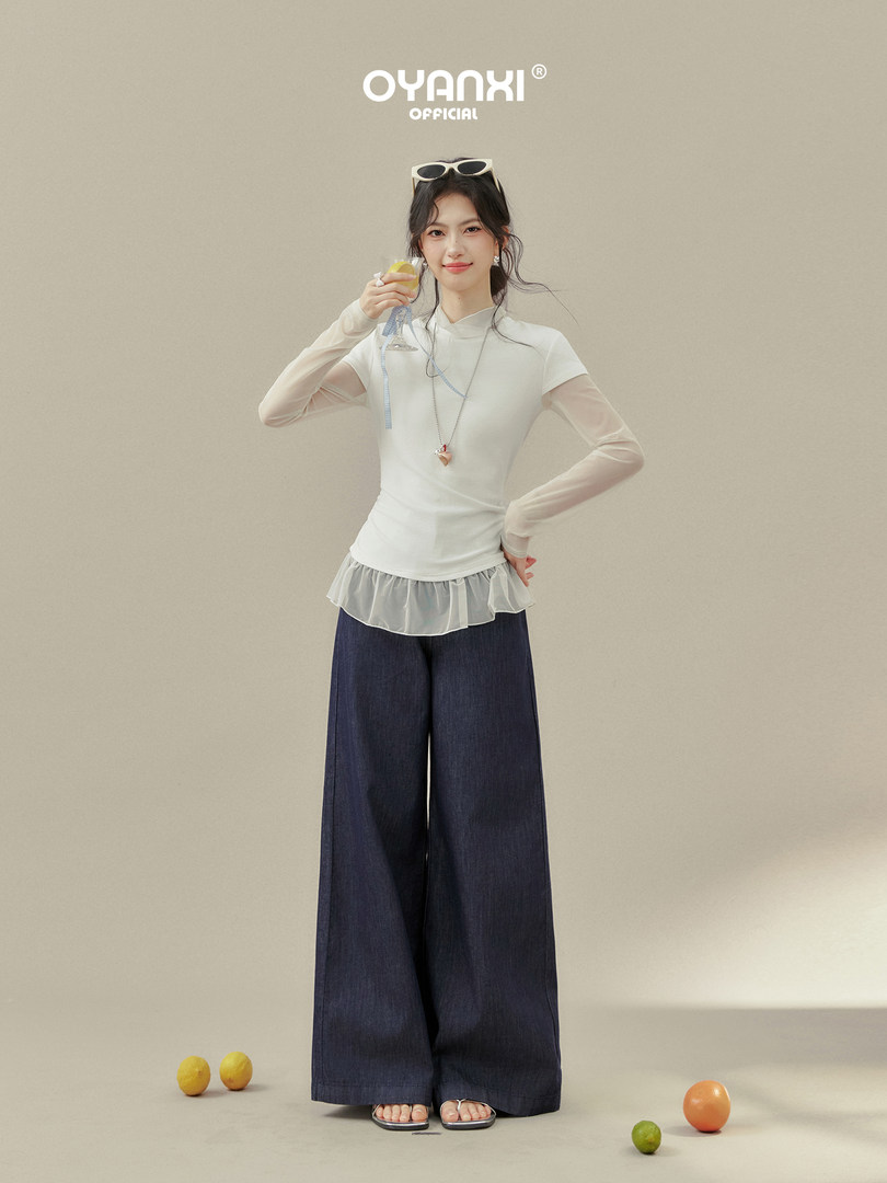 Female model wearing a white sheer layered top with wide-leg dark pants