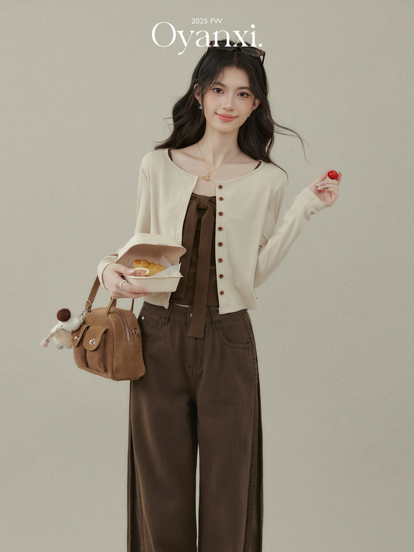 Model wearing a cream cardigan and brown wide-leg pants with a tan handbag