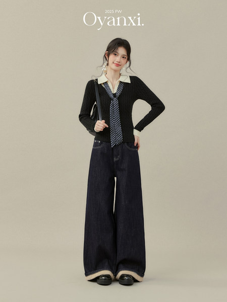 Model wearing a black knit top with a polka dot tie and wide-leg dark jeans