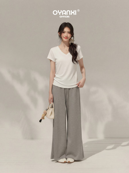 Model wearing a white V-neck T-shirt with gray wide-leg pants