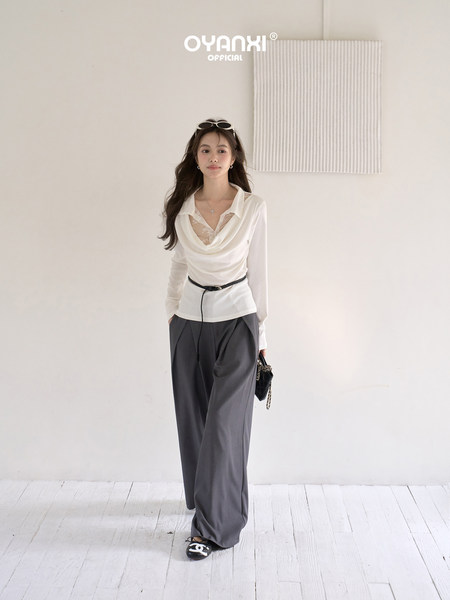 Model wearing a white draped long-sleeve top with gray wide-leg pants