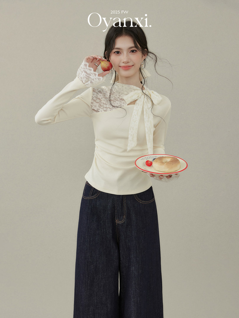 Model wearing a cream lace-trim long-sleeve top with dark wide-leg jeans