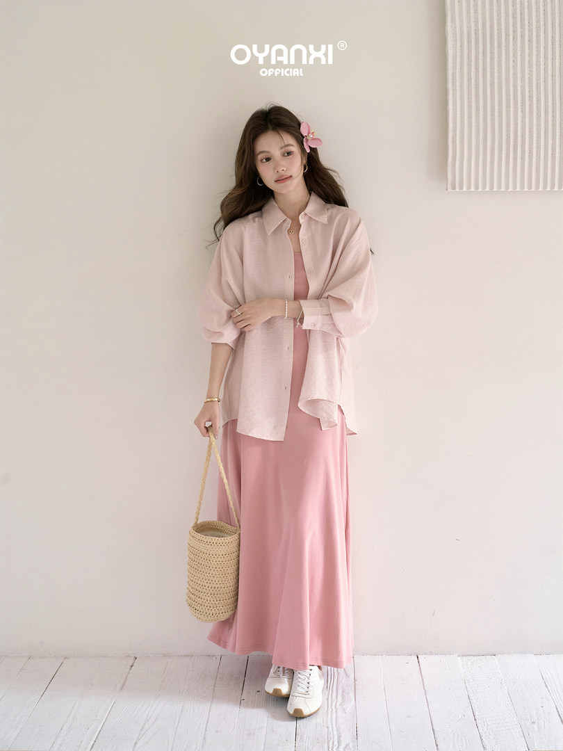 Model wearing a light pink layered dress outfit with a sheer button-up shirt