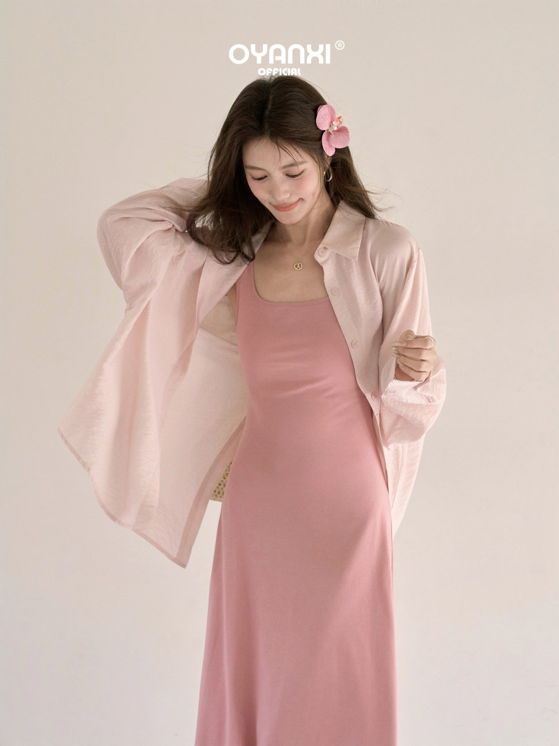 Model wearing a pink slip dress with a light pink sheer button-up shirt