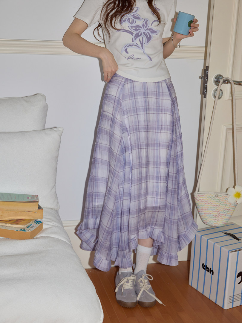 Model wearing a white graphic tee and lavender plaid skirt with sneakers