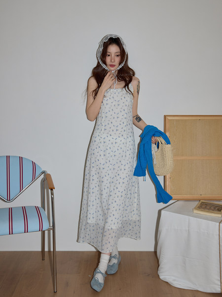 Model wearing a white floral dress with bonnet and blue shoes