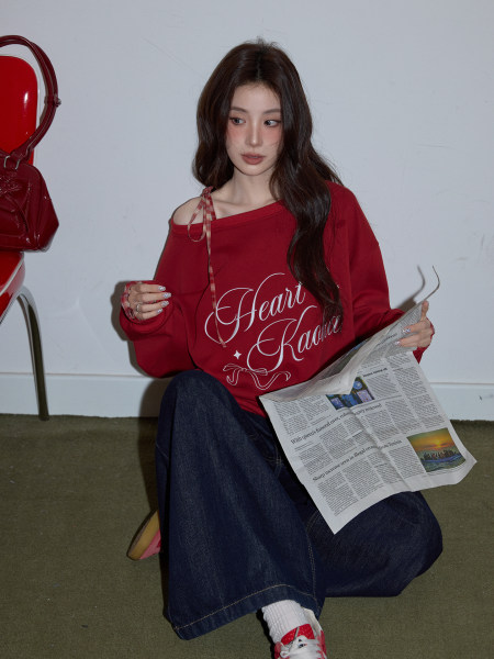 Red off-shoulder graphic sweatshirt worn by a model with jeans