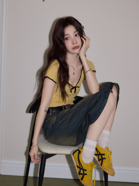 Model wearing a yellow short-sleeve top with dark denim skirt and yellow sneakers