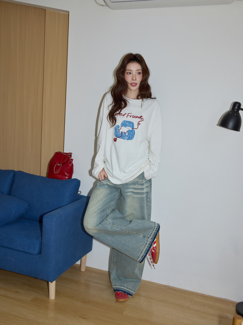 Model wearing a white graphic long-sleeve top and loose light-wash jeans