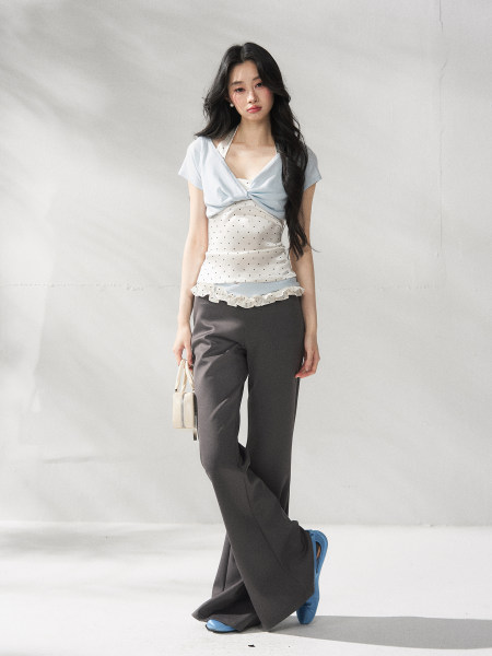 Model wearing a light blue twist-front top with dark wide-leg pants and blue heels