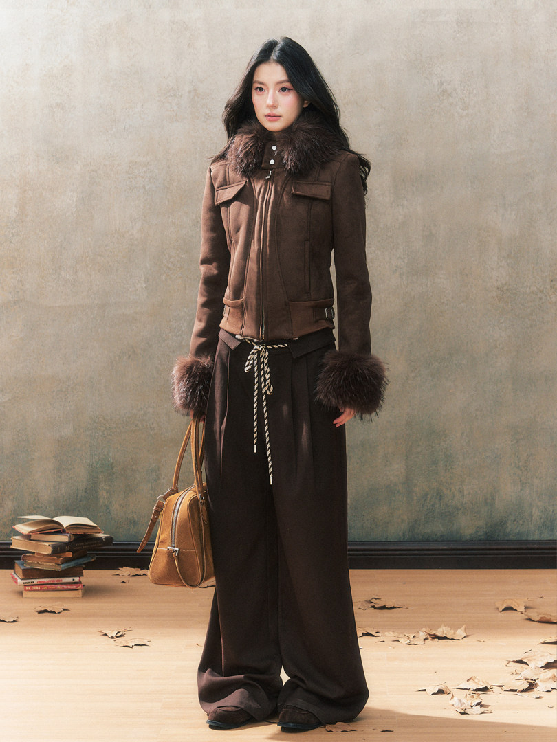 Fashion model wearing a brown fur-trim jacket with wide-leg black pants and a handbag