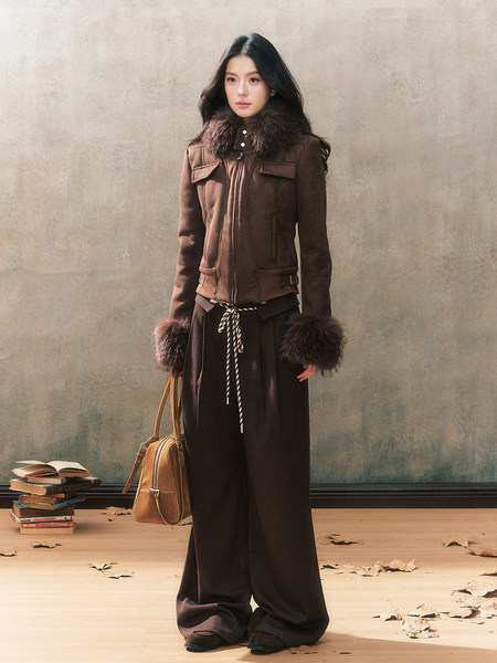 Fashion model wearing a brown fur-trim jacket with wide-leg black pants and a handbag