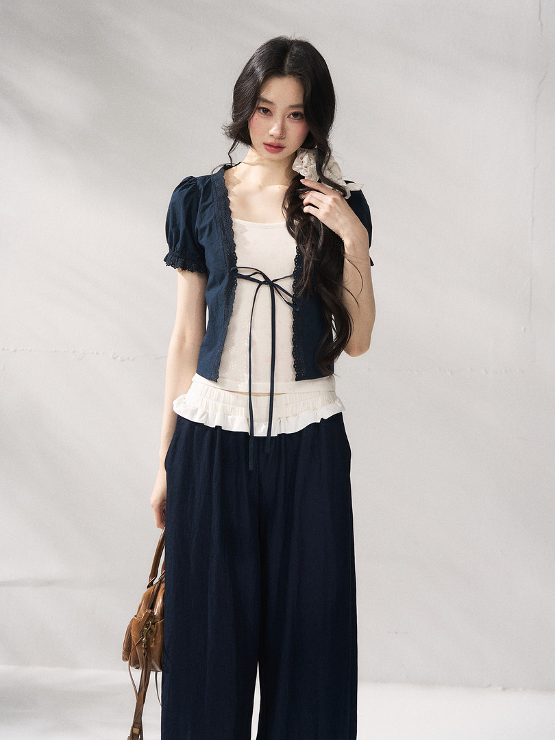 Model wearing a navy and white two-piece outfit with a tied top and wide-leg pants