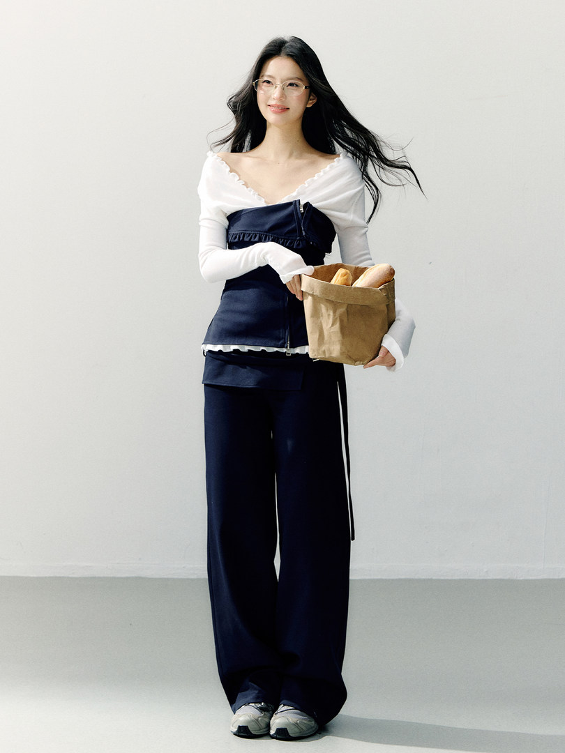 Model wearing a white off-shoulder top and navy wide-leg pants