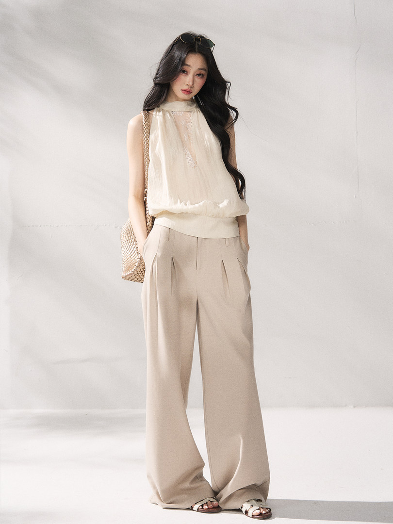 Model wearing a cream sleeveless blouse and beige wide-leg trousers