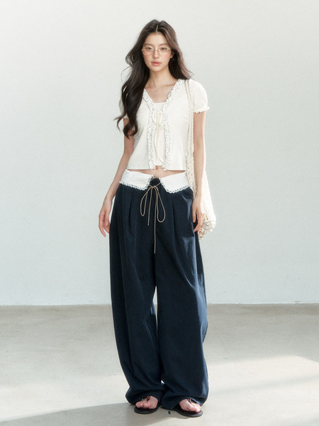 Model wearing a white short-sleeve top with wide navy pants