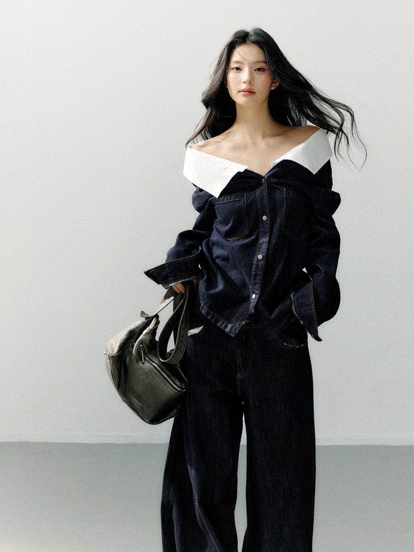 Model wearing a dark denim off-shoulder outfit with a black shoulder bag