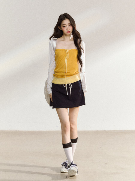 Model wearing a yellow strapless top layered with white sleeves and a black mini skirt