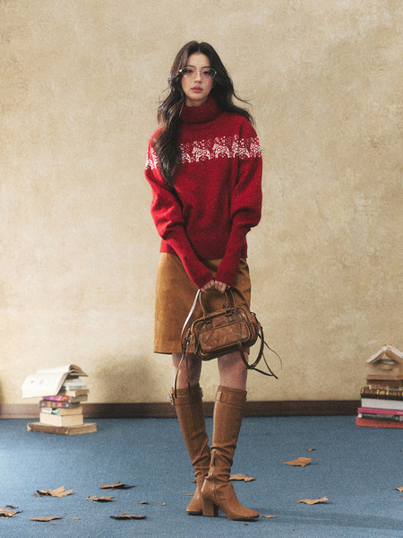 Woman modeling a red turtleneck sweater with a brown skirt, boots, and handbag
