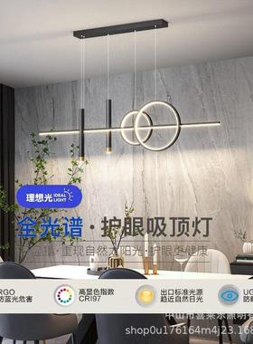 A modern, condensed dining room table with chandeliers in th