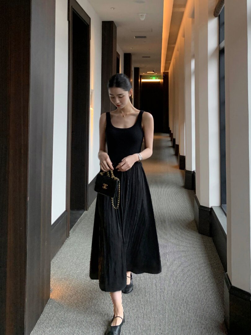 Woman wearing a black sleeveless dress in a hallway