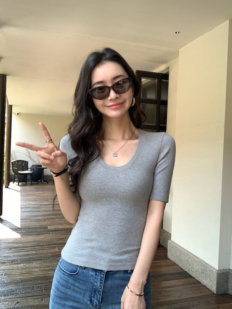 Gray fitted short-sleeve top worn by a woman with jeans and sunglasses