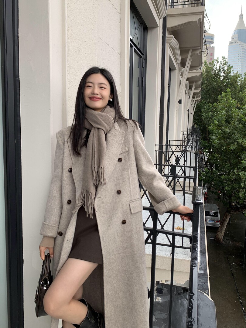 Woman wearing a light beige long coat with a matching scarf