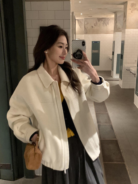 Woman wearing a cream zip-up jacket in a mirror selfie