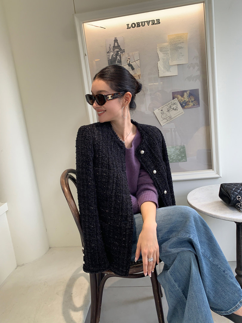 Woman wearing a black textured jacket over a purple sweater and jeans