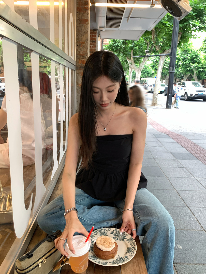 Woman wearing a black strapless top with jeans at an outdoor cafe