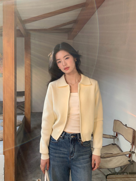 Model wearing a cream zip-up knit cardigan with jeans