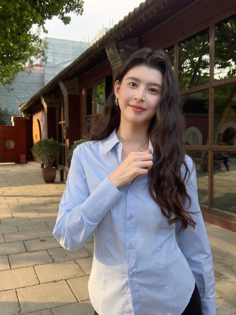 Woman wearing a light blue button-up shirt outdoors