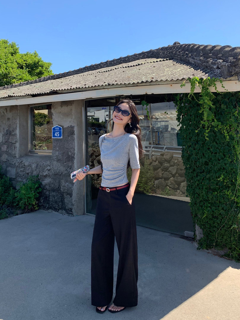 Woman wearing a gray fitted top and black wide-leg pants outdoors