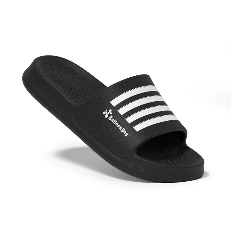 Black slide sandal with white stripe detail on a white background