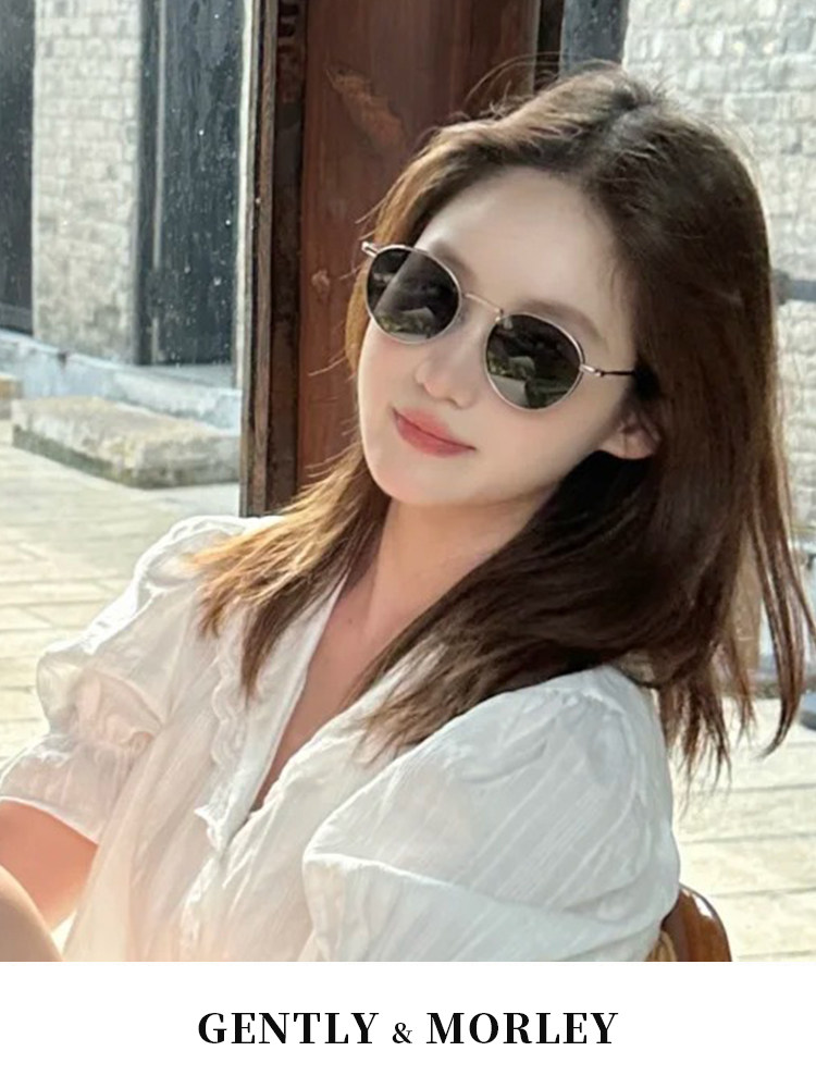 Woman wearing round sunglasses outdoors with a GENTLY & MORLEY brand banner