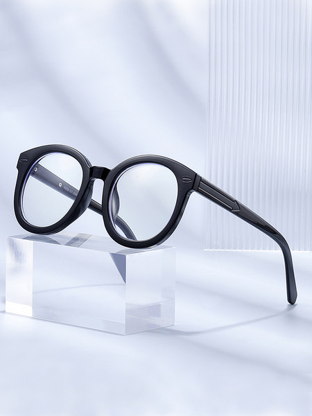 Black round eyeglasses displayed on a clear block