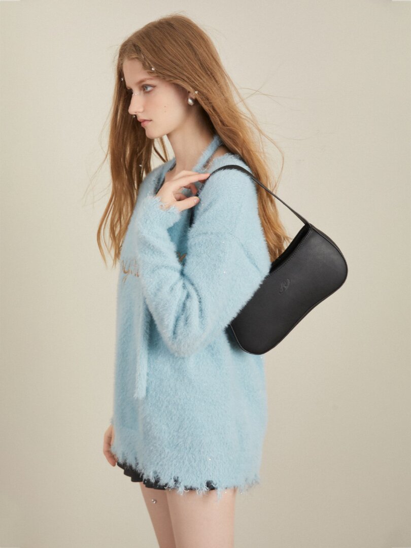 Model wearing a light blue fuzzy sweater dress with a black shoulder bag