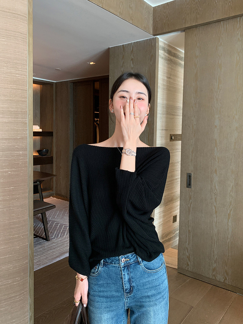 Woman wearing a black off-shoulder knit top with blue jeans