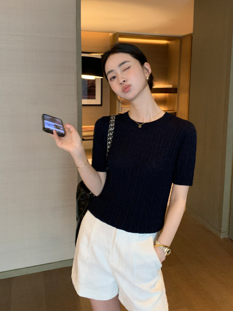 Woman wearing a navy short-sleeve top with white shorts