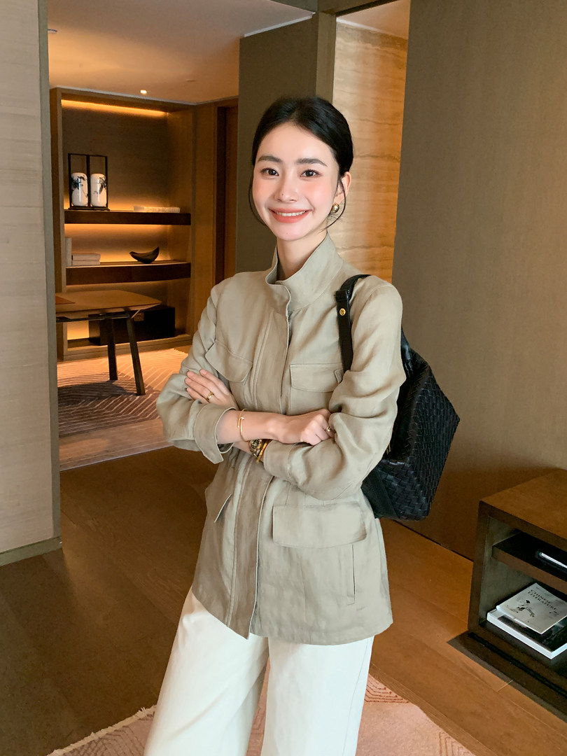 Woman wearing a beige jacket with white pants and a black woven shoulder bag
