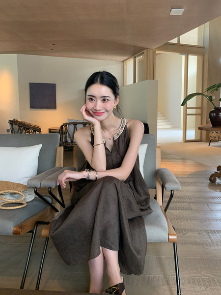 Woman wearing a dark brown sleeveless dress seated indoors