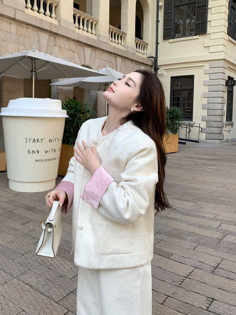 Woman wearing a white wool coat and matching skirt set outdoors