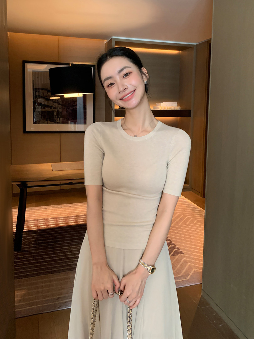 Woman wearing a beige fitted short-sleeve dress in an indoor setting